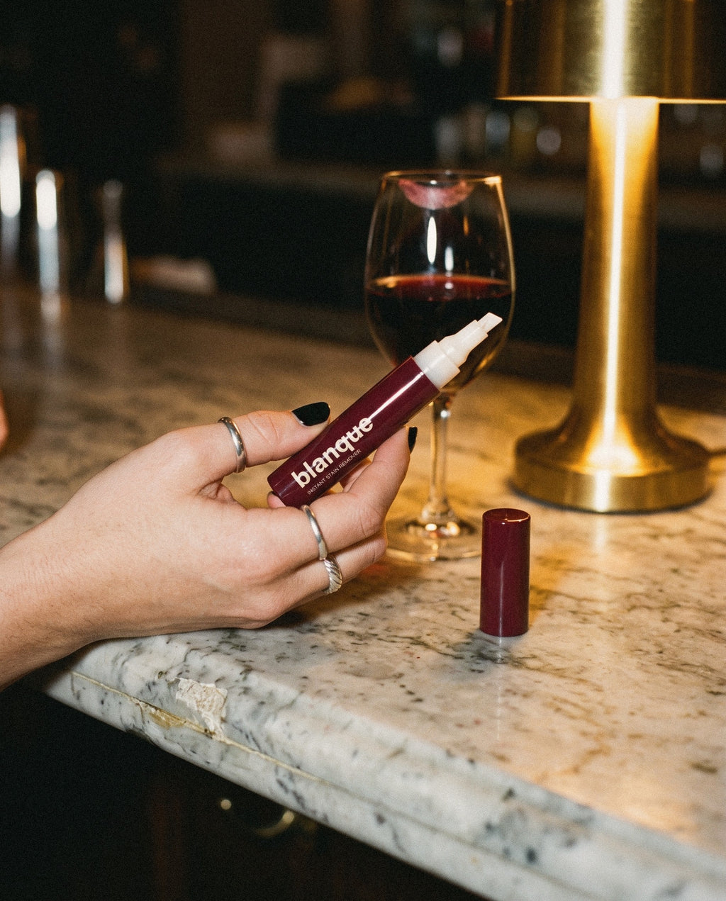 A hand holds the pen uncapped like a lipstick at the bar.