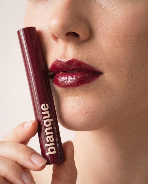 blanque instant stain remover held beside glossy red lips