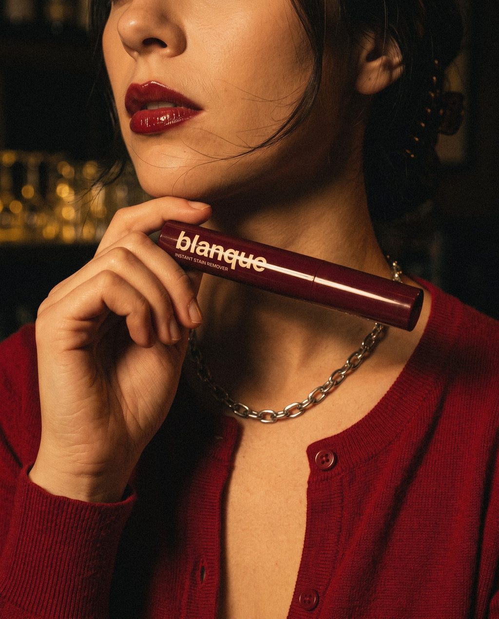 A woman in a red cardigan holding the blanque pen under her chin at a bar