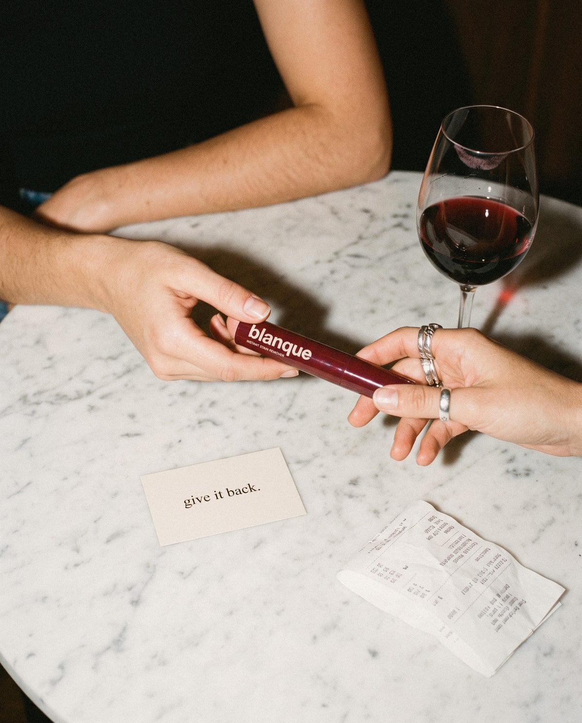 Passing the blanque pen across a marble table, the card says give it back.