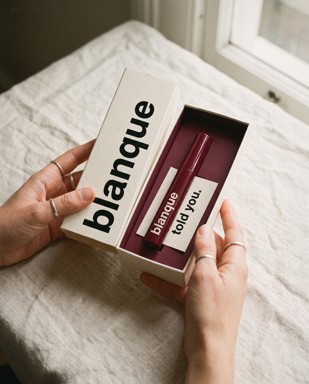 Hands opening the box: bordeaux inside and the card that says told you.